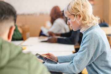 Focused college student studying with a tablet in a classroom - Concentration, modern education, and academic engagement, with the student deeply involved in her work.