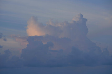 A serene sky with soft clouds tinted with pink hues from the setting or rising sun.