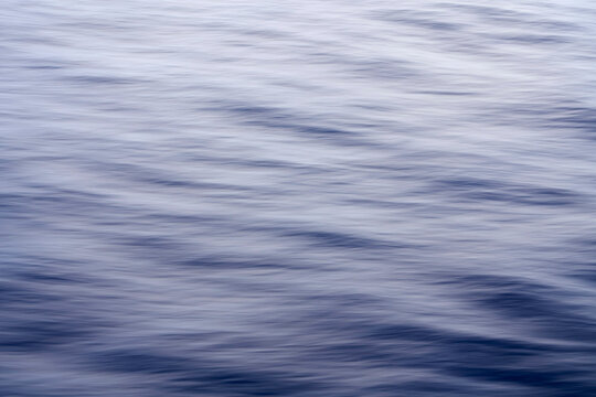 This is a tranquil image showing the smooth, flowing surface of water in shades of blue, capturing the gentle movement of the waves.