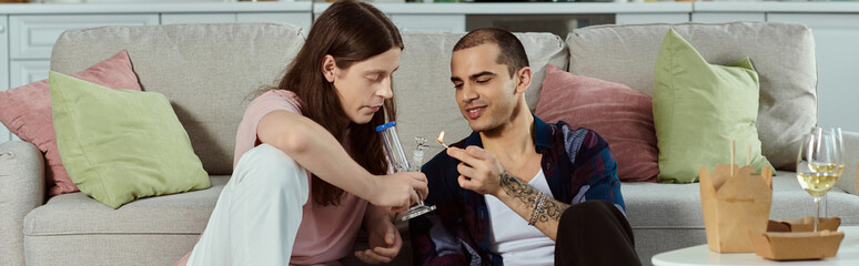 A gay couple in casual clothes enjoying a cozy moment together on a couch at home.