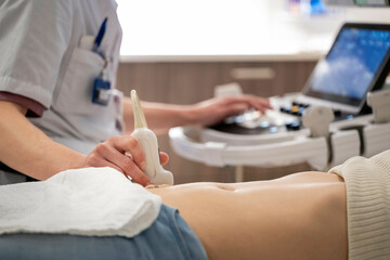 A medical professional conducts an ultrasound examination on a patient lying down, the ultrasound probe on the patient's abdomen.