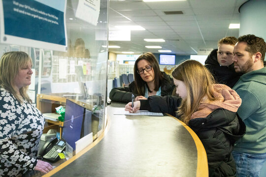 Family registering with a receptionist at a service desk of a medical practice