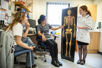 Doctor and assistant show skeleton picture to patient in a medical practice