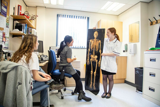 Doctor and assistant show skeleton picture to patient in a medical practice