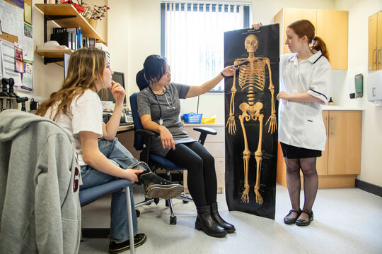Doctor and assistant show skeleton picture to patient in a medical practice