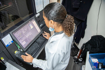 Female technician operating advanced machinery in a medical practice, UK