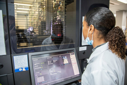 Female technician operating advanced machinery in a medical practice, UK