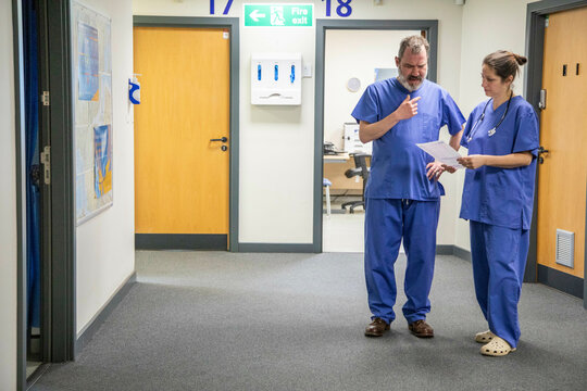 Two healthcare workers consulting in hospital corridor, medical practice UK