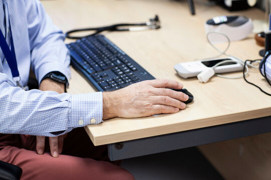 Doctor working at a computer desk with medical equipment nearby.
