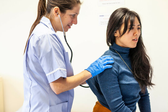 Nurse checking patient's heartbeat with stethoscope