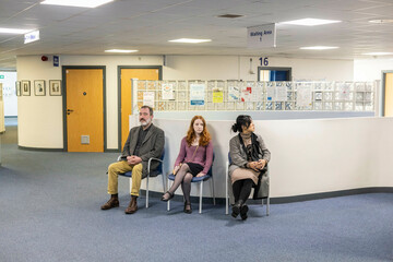 Three people waiting in a hospital hallway of a medical practice