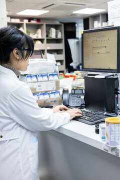 Scientist works at a computer in a lab and dispatch area of a medical practice