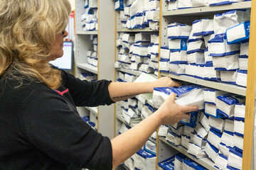 Woman stocking pharmacy shelves with medication.