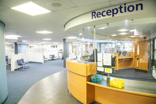 Modern hospital reception area with curved desk and signage.