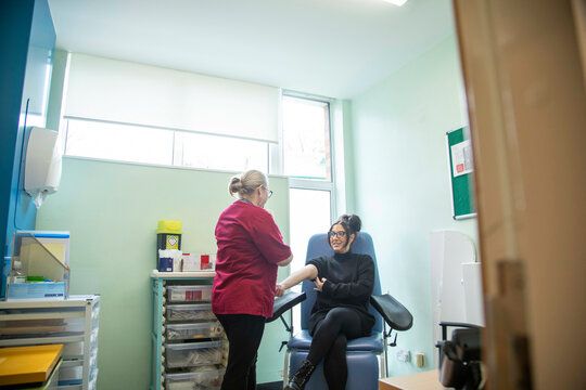 Nurse performing blood test to patient in clinic.