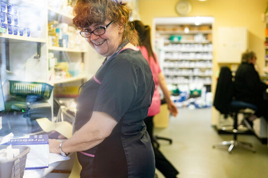 Smiling woman in a medical clinic with colleagues in the background.