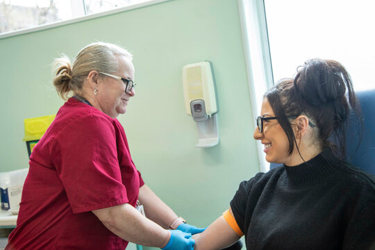 Healthcare worker drawing blood from a smiling patient.