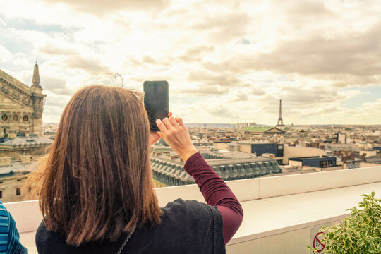 Woman taking a photo of cityscape with smartphone
