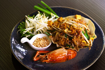 Close up beautiful Pad Thai with beautiful decoration on black table, premium menu Pad Thai with a big prawn.