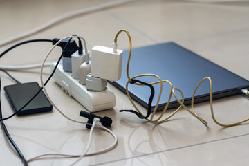 Electrical outlet with many chargers connected to it for a smartphone, laptop, microphone