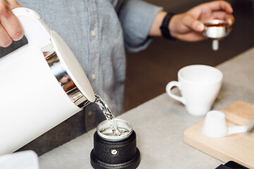 Pouring Boiling Water From Electric Kettle Into an Italian Coffee Makers Tank