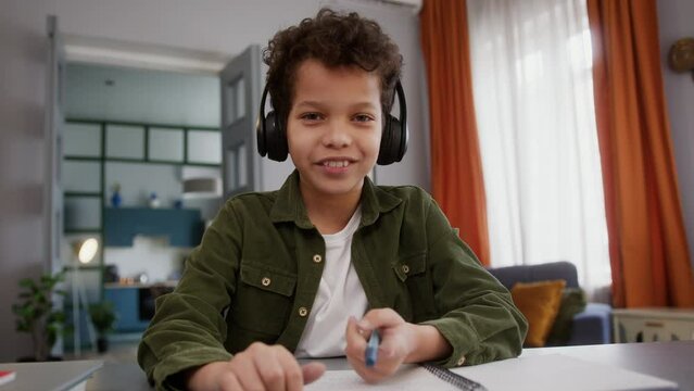 Webcam view POV web cam video call conference distant lesson class American African little boy in headphones talking with online teacher internet tutor son kid child pupil home education studying