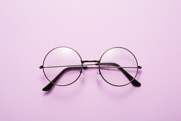 Glasses in round thin metal frame isolated on purple surface.