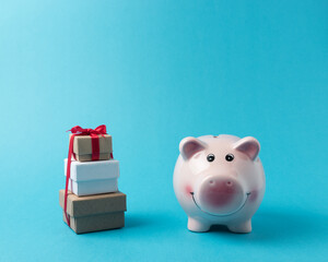 Piggy bank with gift boxes on blue background. Christmas or New Year minimal concept.