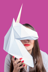 The girl holds  a white 3d papercraft model of Unicorn. Minimal Art concept.