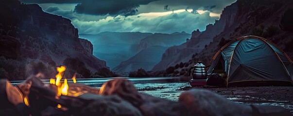 Scenic campsite by a river with a tent, campfire, and colorful sunset in a picturesque canyon landscape. - Powered by Adobe