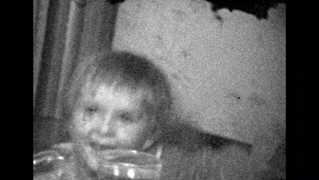 Active hyperactive child jumping, smiling. Crazy happy little girl rejoicing in home, indoor. Carefree childhood happiness. Mischievous noisy kid. Vintage black white film. Family archive. Retro 1980s