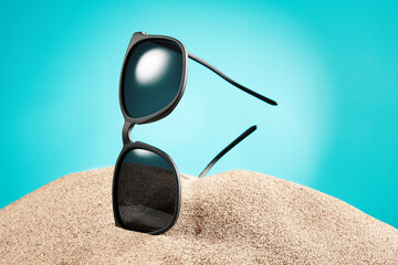 Sunglasses, shades with black frame, lenses in sand.