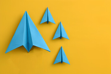 A yellow background with four blue paper airplanes on it