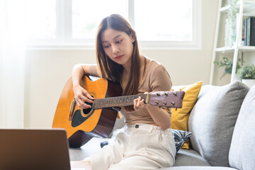 Hobby relaxation concept, happy asian young woman in casual clothes, playing acoustic guitar with...