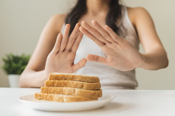 Gluten allergy, asian young woman hand push out, refusing to eat white bread slice on plate in...