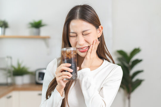 Health asian young woman touching her mouth, expression, suffering from toothache, decay or sensitivity cavity molar tooth or inflammation drink cold, sparkling water at home.Sensitive teeth people.