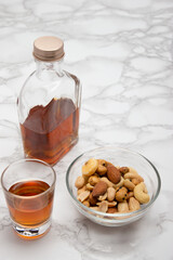 大理石の上にウィスキーミニボトルとショットグラスとおつまみ