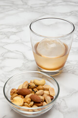 大理石のテーブルの上の丸い氷のウィスキーオンザロックとおつまみ