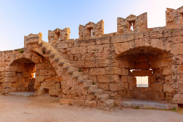 Stone staircase and archways in ancient wall in Rhodes, Greece, with boat visible through the window