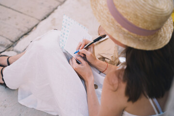 Woman tourist signs postcard or letter to friend from Italy, Europe.
