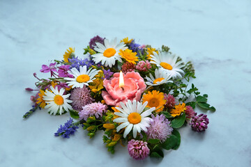 flower shape candle with colorful meadow flowers on abstract marble background close up. esoteric...