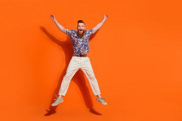 Full size photo of impressed cool man with red beard wear stylish shirt jumping like star hands up...