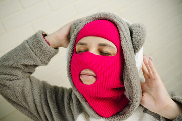 Woman in pink Balaclava Dancing Against a White Brick Wall