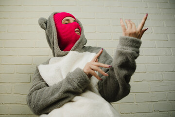Woman in pink Balaclava Dancing Against a White Brick Wall