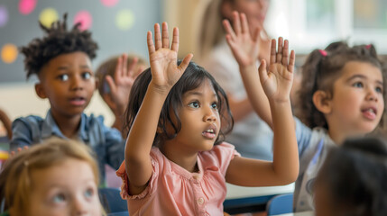 A young girl with raised hands attentively participates in a classroom activity with her pre-school peers