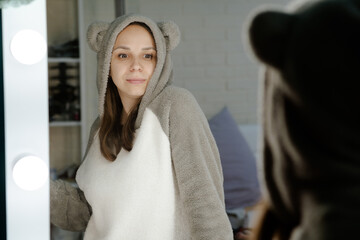 Woman in a Grey Hoodie Looking in a Mirror. A woman wearing a grey hoodie examining her reflection...