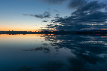 Silhouette with cloud reflections on calm bay
