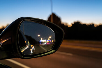 Sparkling and defocused vehicle lights in rear vision mirror at night.