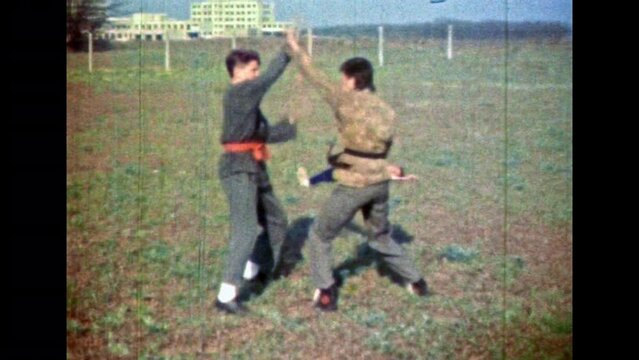 Karate sparring between professional man athlete fighters. Martial workout training with aikido partner. Two men martial combat fighting in green nature outdoor. Vintage film. Retro 1980s archive