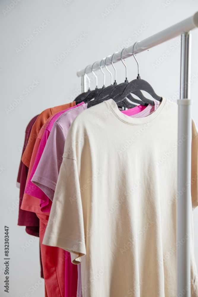 Wall mural row of t-shirts on a hanger against a background of a white wall hanger